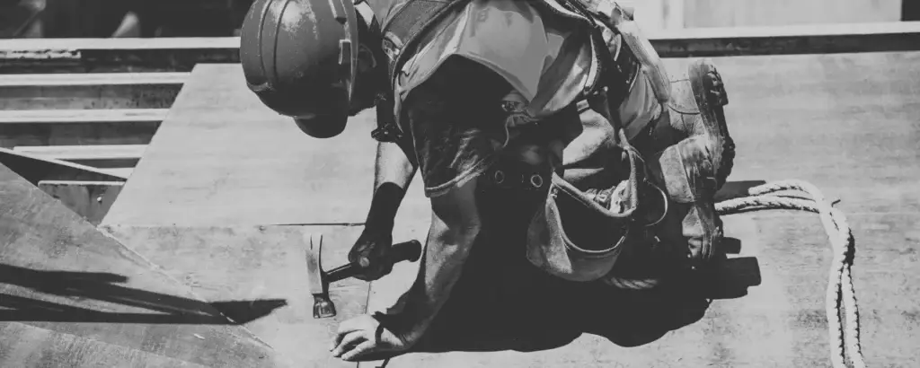 Trabalhador da construção civil aplicando concreto em uma superfície externa.