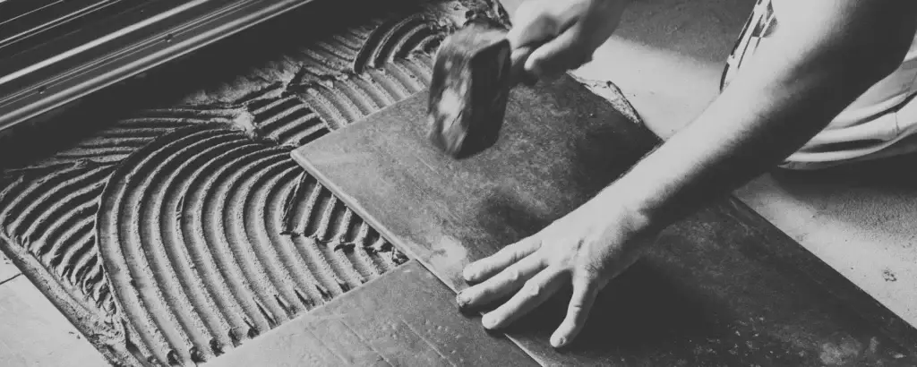 Professional tile installation with precision using mortar and a rubber mallet.